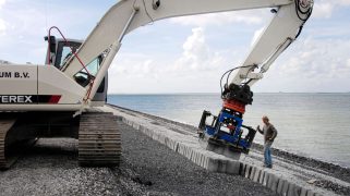 A machine helping place concrete in front of an area with sea level rise
