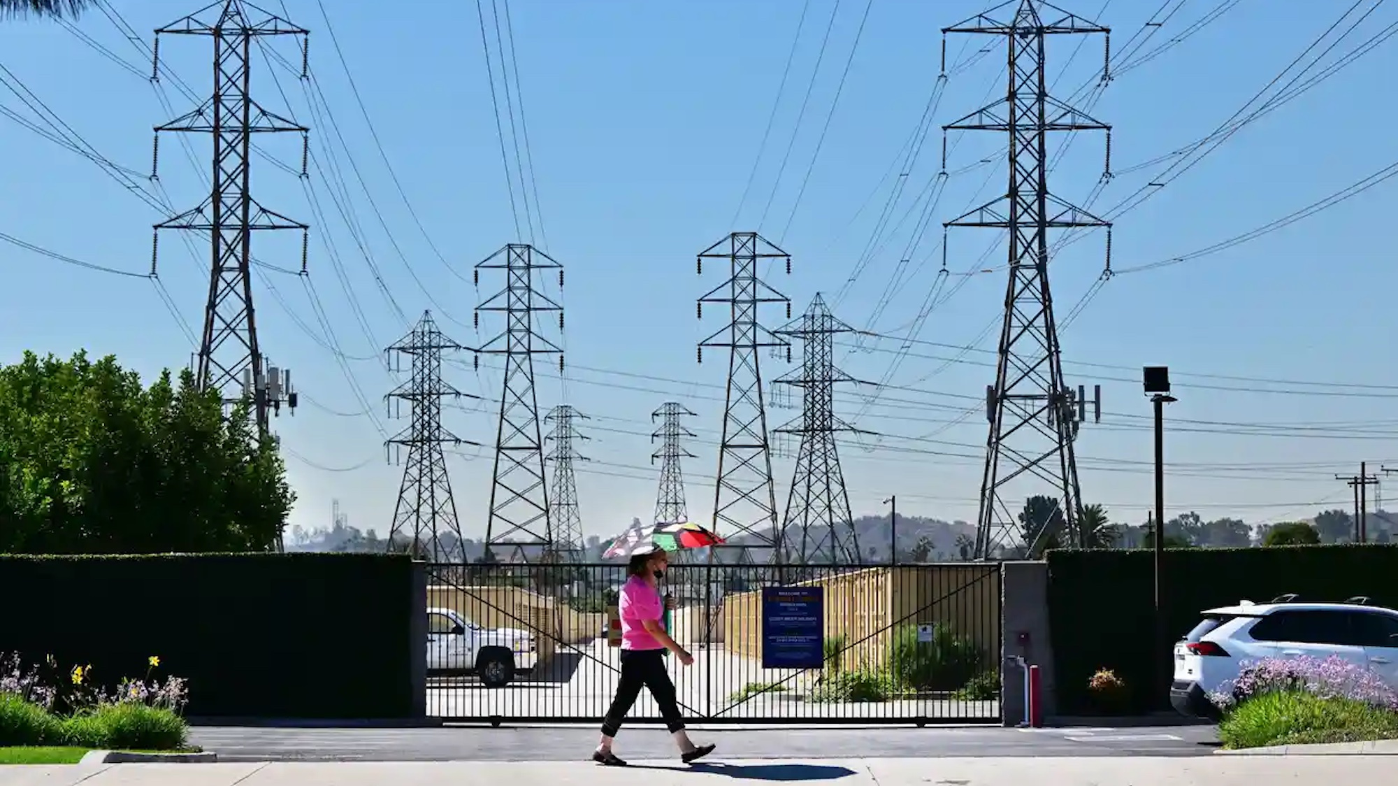 A woman walking with an umbrella outside, the sky is very blue