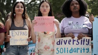 A photo of three women of color holding signs that say "Expand Opportunity," "Defend Diversity," and "Diversity Solidarity" out an outdoor protest.
