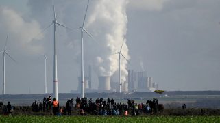 People ar a demonstration with a factory in the background