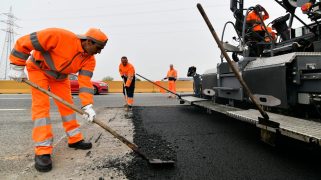 Workers lay down asphalt infused with plastic waste on a roadway in Turin, Italy.