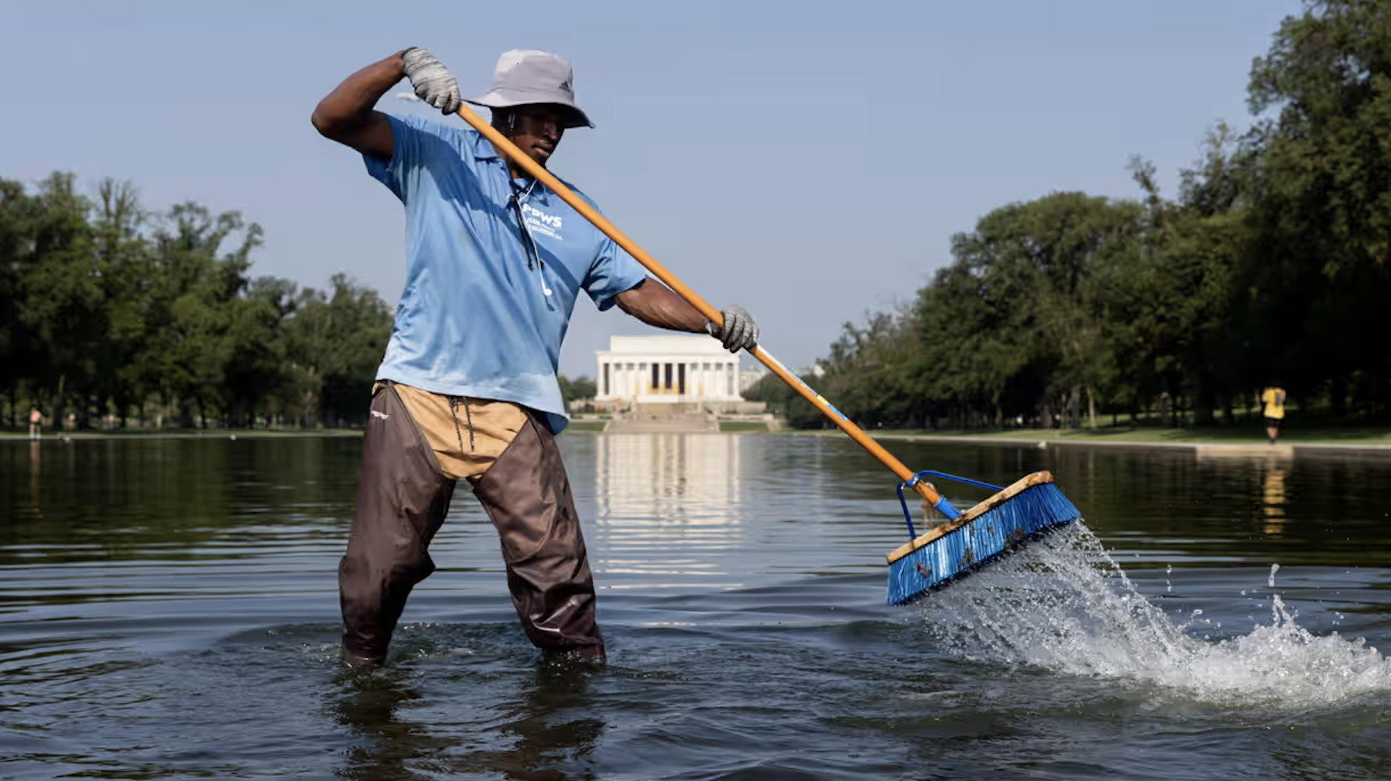 A worker clears algae and debris from the Lincoln Memorial Reflecting Pool on the National Mall, during a heat advisory in Washington DC