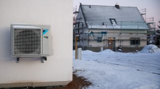 An air-source heat pump hangs on a house wall in snow and ice in a newly developing single-family housing area. During the night, temperatures in Leipzig dropped to minus 9 degrees under clear skies.