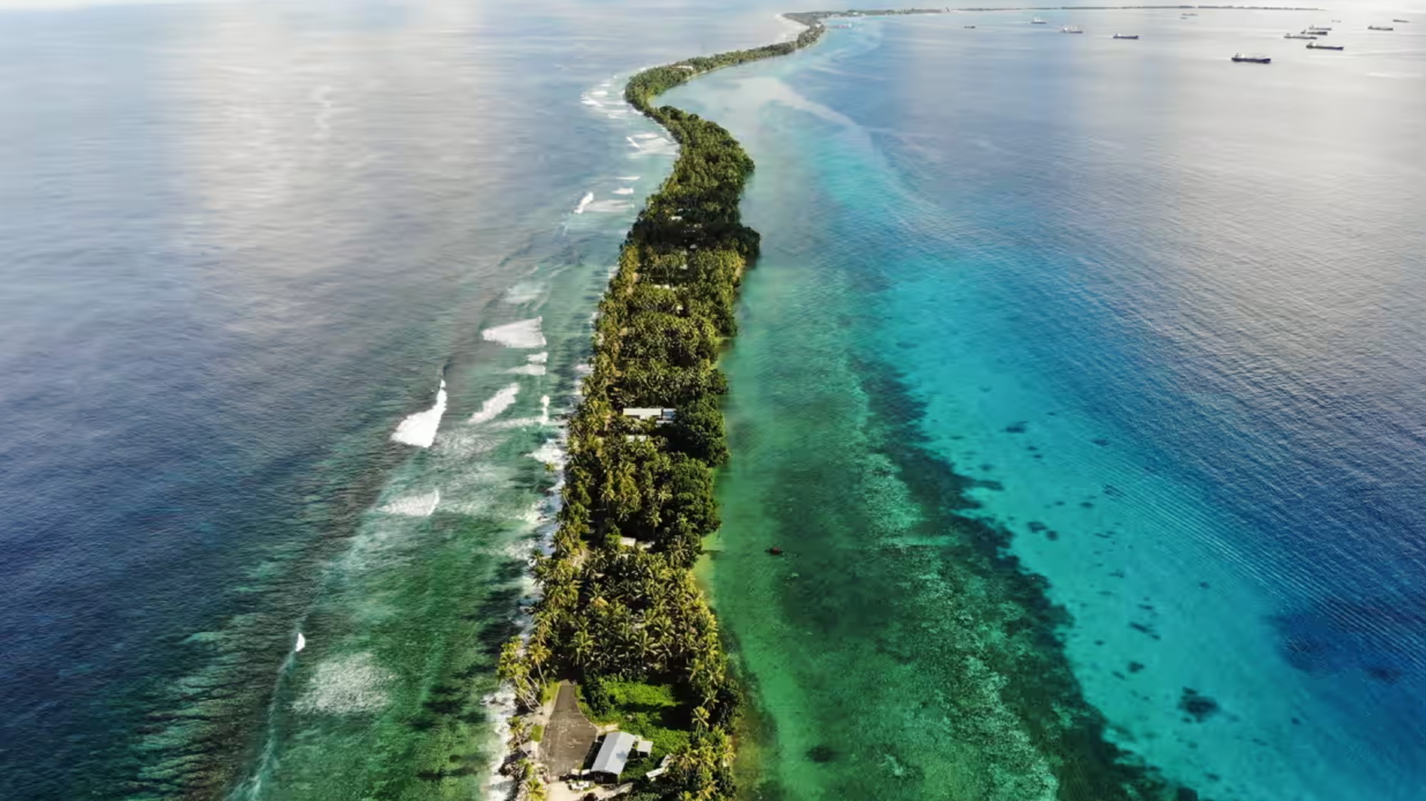 A small strip of green land cuts through a blue-green ocean.