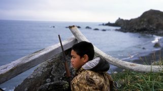 Steven James, 12, waits to hunt geese on St. Lawrence Island, in Alaska, sitting hidden behind a wood bar and a whale bone.