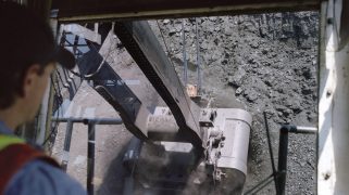 An electric shovel operator passes through a seam of coal with a person operating the machine
