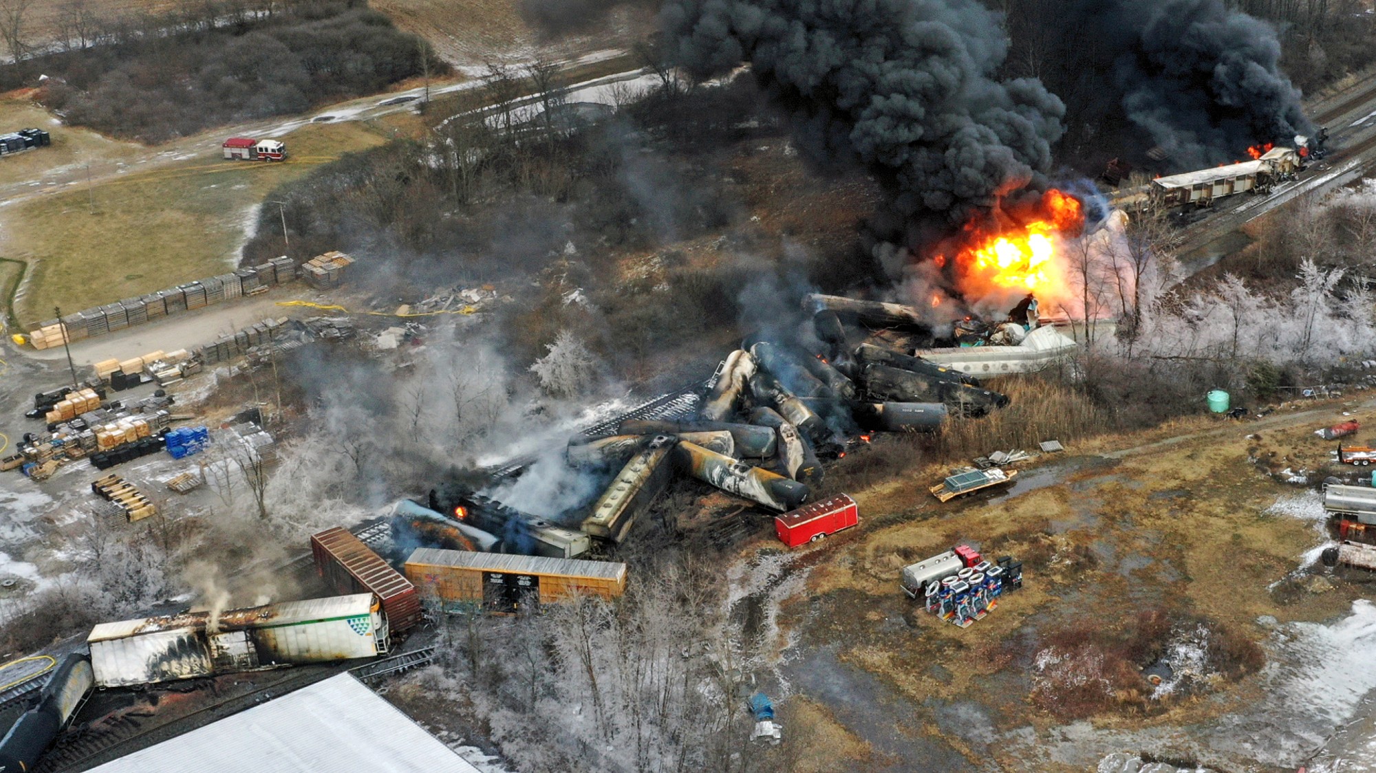 A train crash in an open field, fire in the upper right hand corner.
