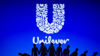 Cut out paper figures are held up against the Unilever logo projected in white on a blue screen.