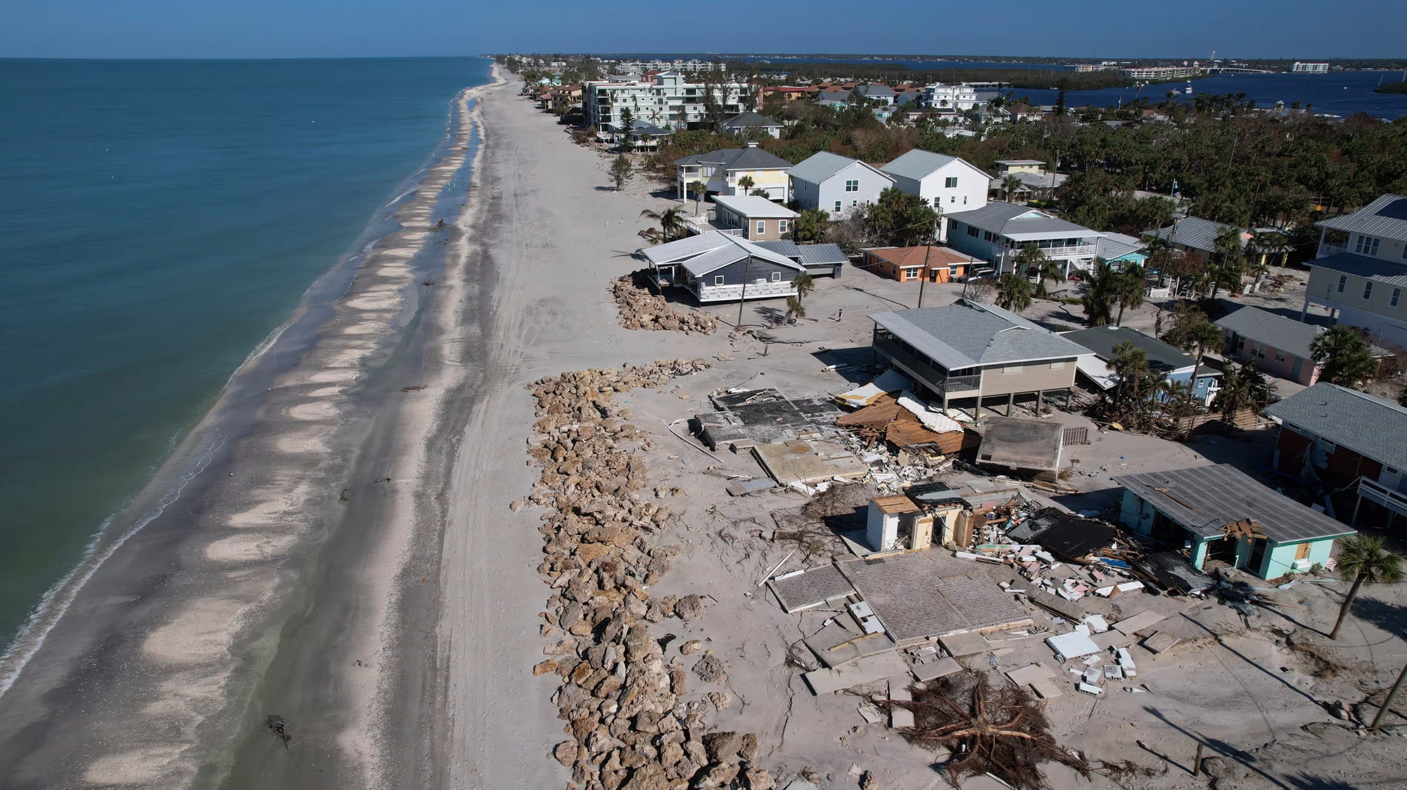 A sandy beach with damaged homes.