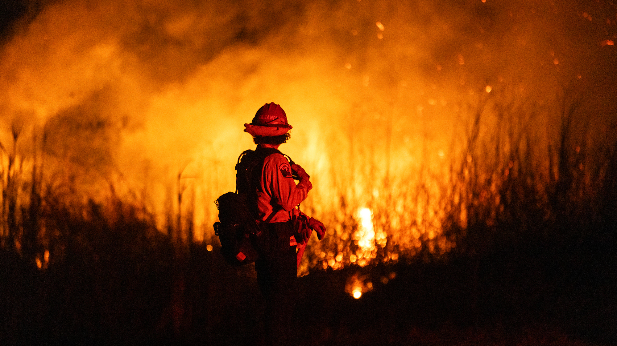 A firefighter stands in front of flames