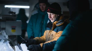 Man in yellow jacket looks at ice