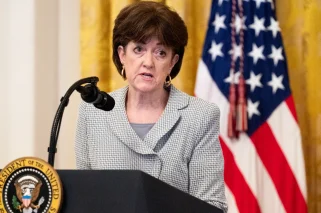 A white woman with brown hair standing at a podium.