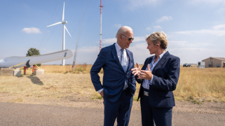 A white man and a white woman talk with each other next to a windmill.