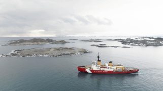 A red boat floats in grey water.