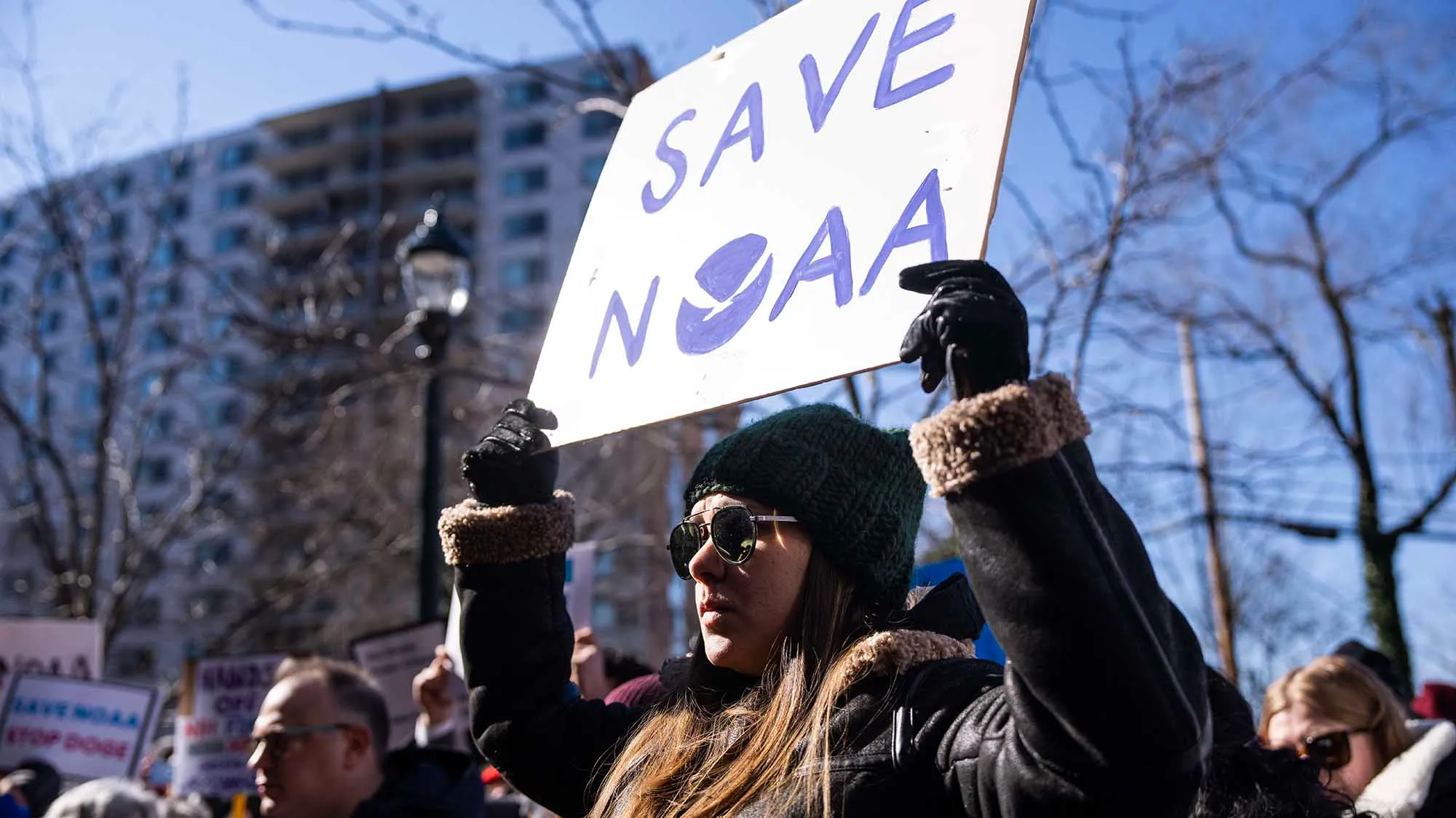 A person holds up a sign that says "Save NOAA"