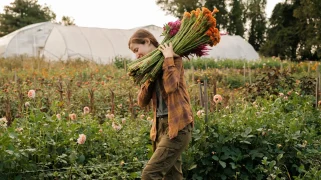 A woman with red hair carries a bundle of flowers