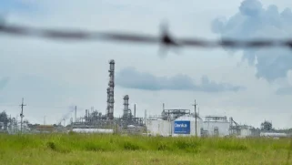 A smokestack in front of a green field