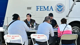Folks sitting at a table in front of a FEMA bus