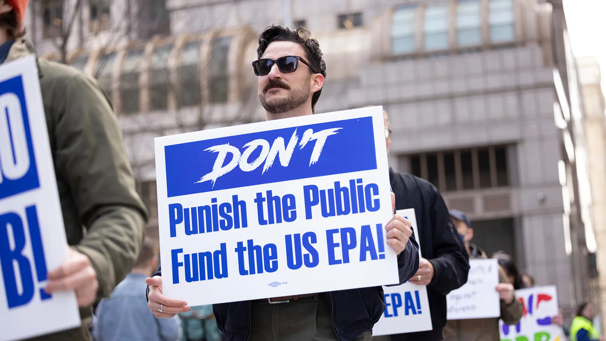 A protester with a sign that says "don't publish the public fund the US EPA"