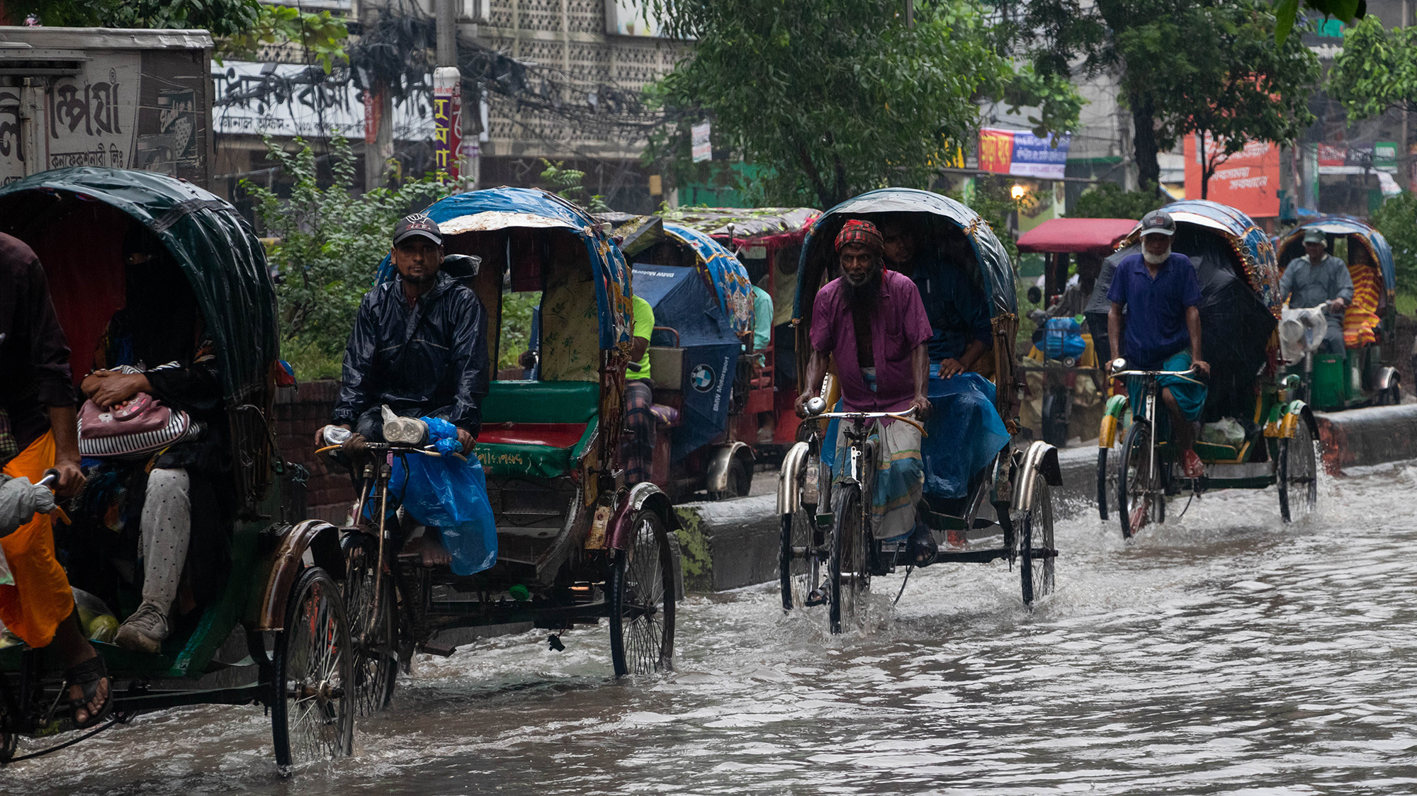 May 27, 2024, Narayanganj, Dhaka, Bangladesh: Streets are inundated with rainwater, forcing vehicles and citizens to navigate through waist-deep water as heavy rainfall causes flooding in Narayanganj, a neighboring city of the capital Dhaka in Bangladesh. As tropical cyclone Remal made landfall in Bangladesh on Sunday, bringing torrential rain and heavy winds, waterlogging has severely impacted some neighboring areas of Dhaka city. Passengers in rickshaws and vans are seen struggling to commute. The relentless downpour has led to significant disruption, with daily life and transportation grinding to a near halt. Cyclone Remal hit the coast with wind speeds of up to 115 kilometers per hour. Millions are without power as authorities shut down electricity supply to coastal areas in advance to avoid accidents. (Credit Image: © Joy Saha/ZUMA Press Wire)