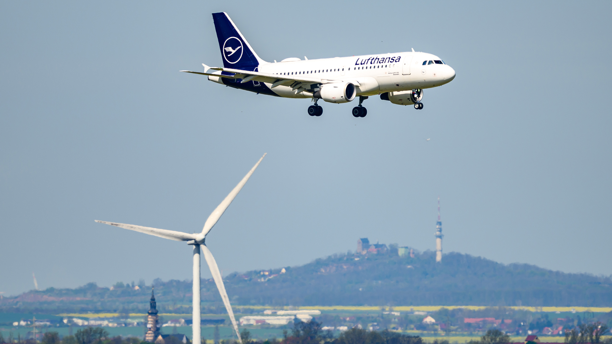 A plane flies over a wind turbine
