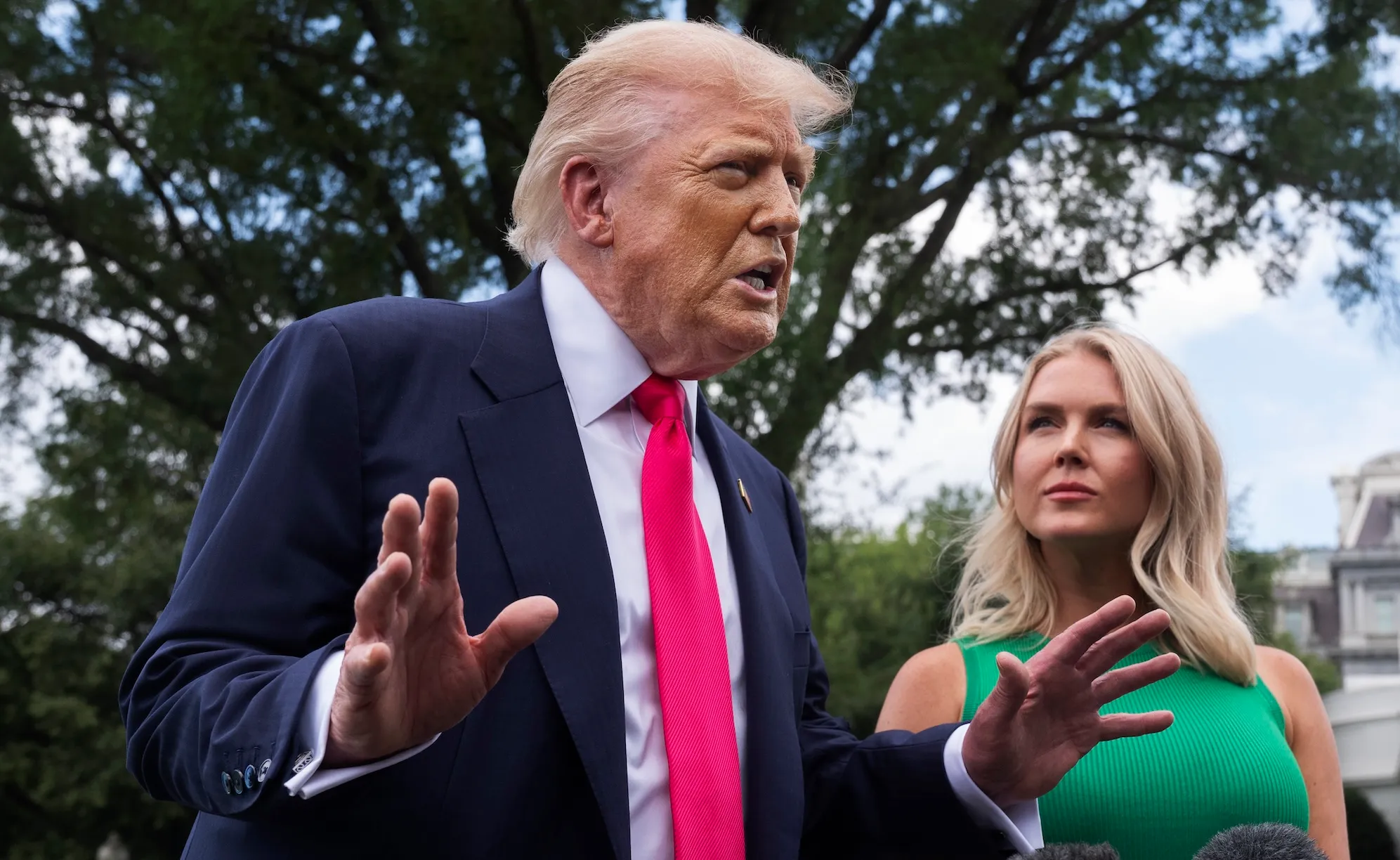 Donald Trump speaks while a blond woman looks at him.