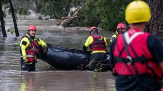 Four people wearing emergency gear stand in thigh-high water.