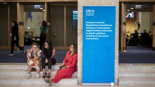 Tired people sit on stairs by a UN sign
