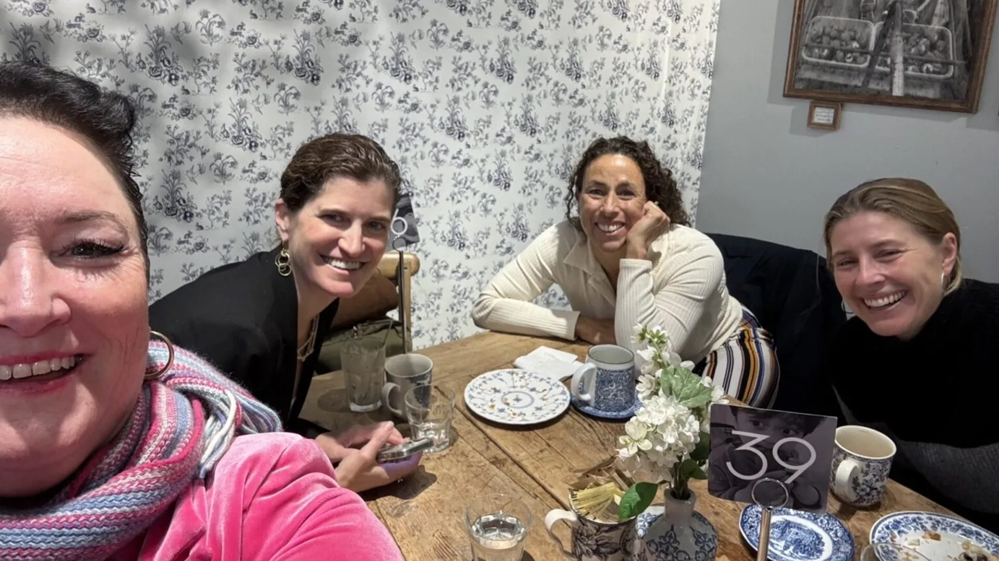 Three woman sitting around a table smiling