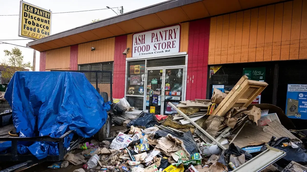 An orange building with the sign "Ash Pantry Food Store" and debris in front of it.