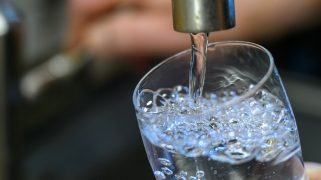 PRODUCTION - 24 July 2025, Saxony, Chemnitz: Drinking water runs into a glass in a kitchen in Chemnitz. The energy supplier Eins operates the city's drinking water network, which is around 1500 kilometers long.