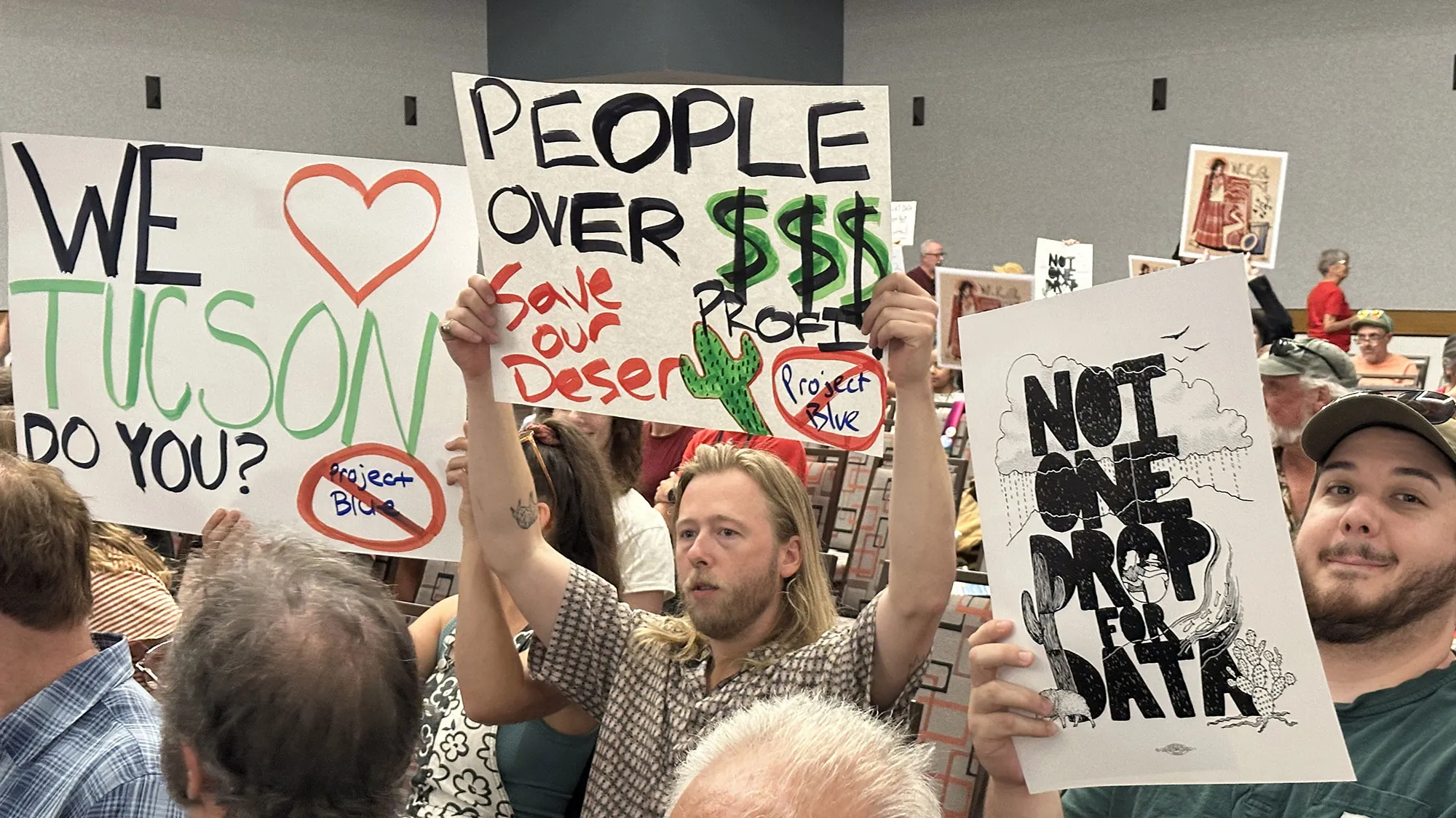 Seated white people with signs opposing a proposed data center