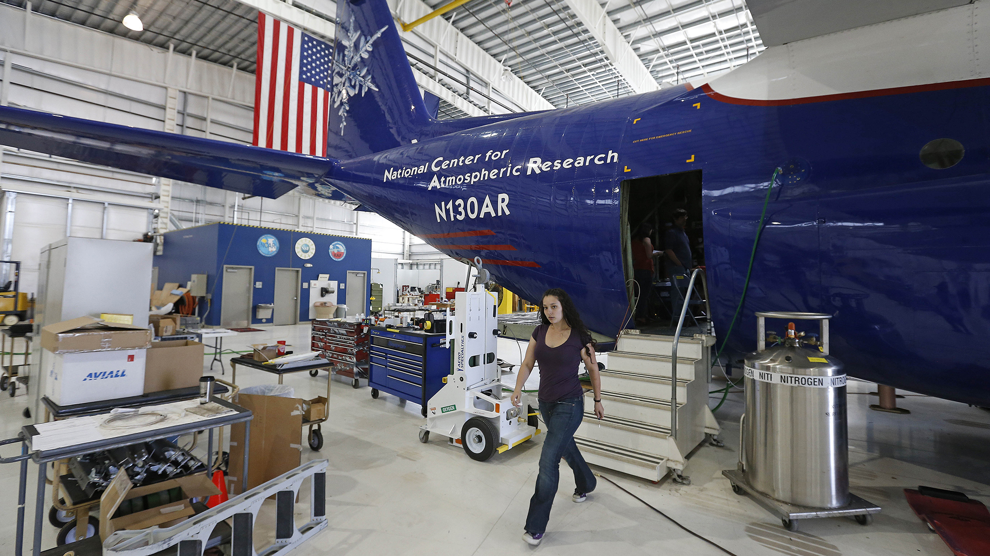 A person walks out of a plan with National Center for Atmospheric Research emblazoned on it.