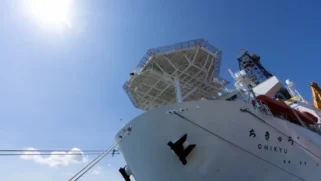 "An upward view of a large, white ship and a bright, blue sky.